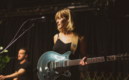 UCD alumna Megan O'Neill performing on stage holding a guitar.